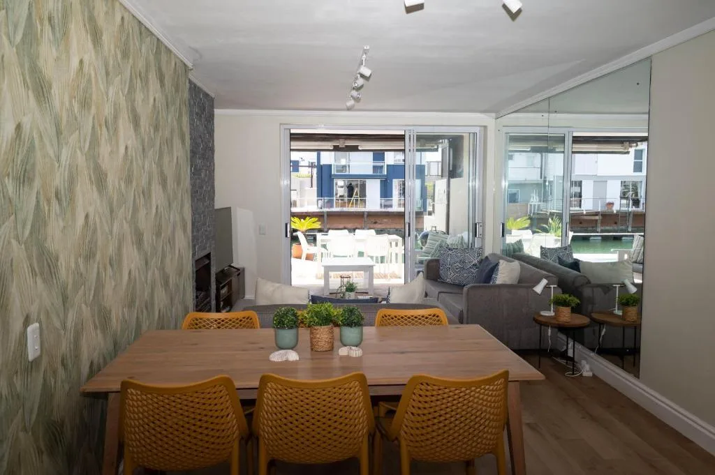 Modern dining area with wooden table and mustard chairs overlooking deck