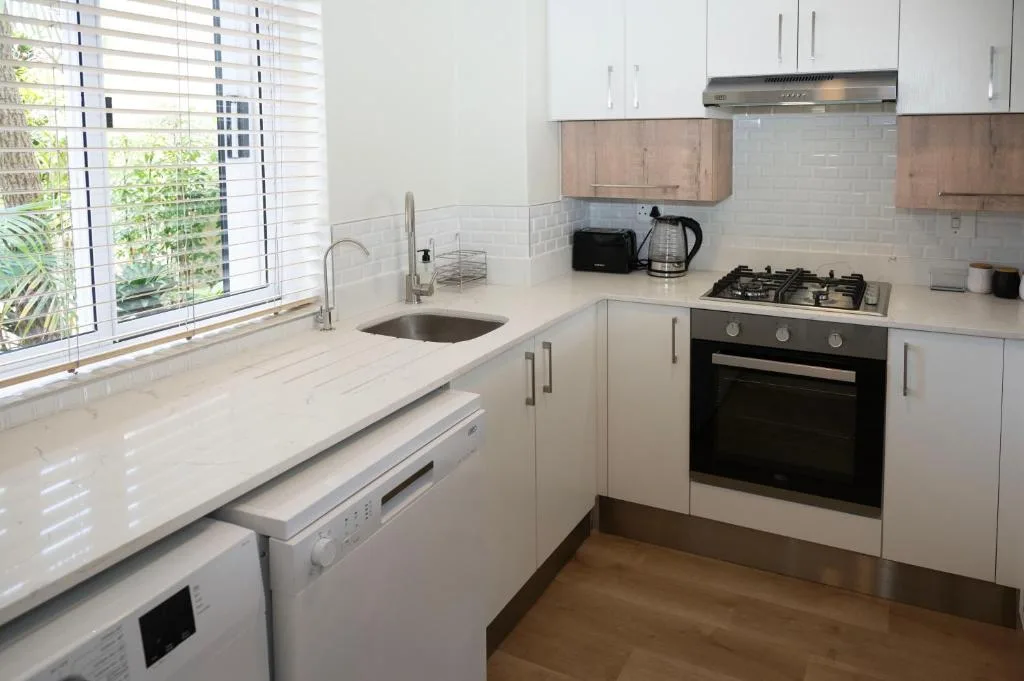 Modern white kitchen with gas stove, sink, and garden view windows