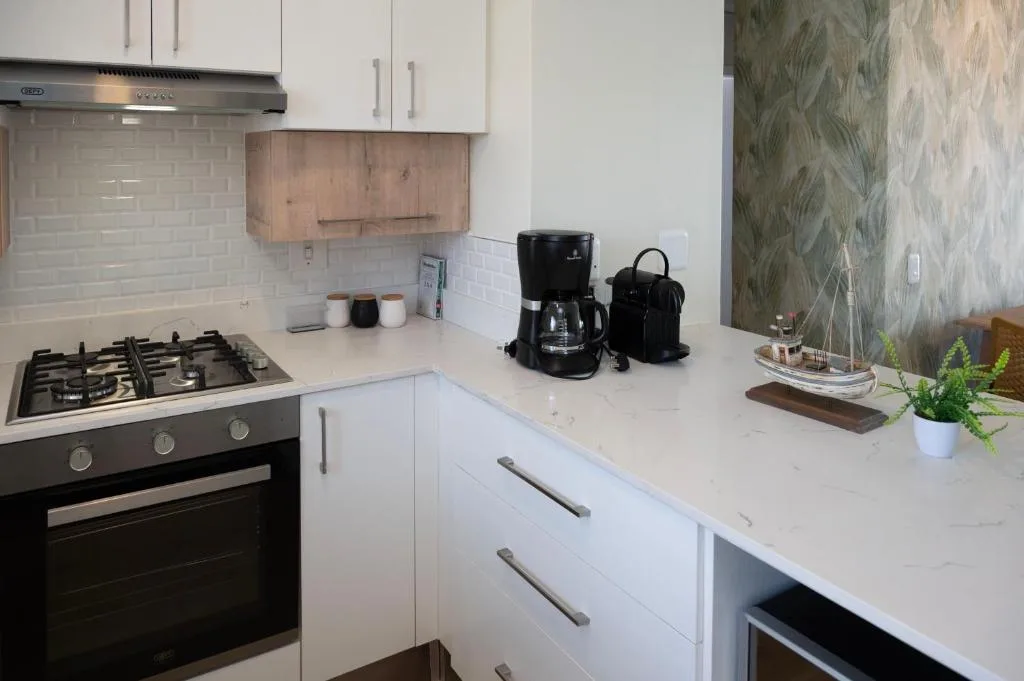 Modern kitchen with white cabinetry, gas stove, and marble countertop