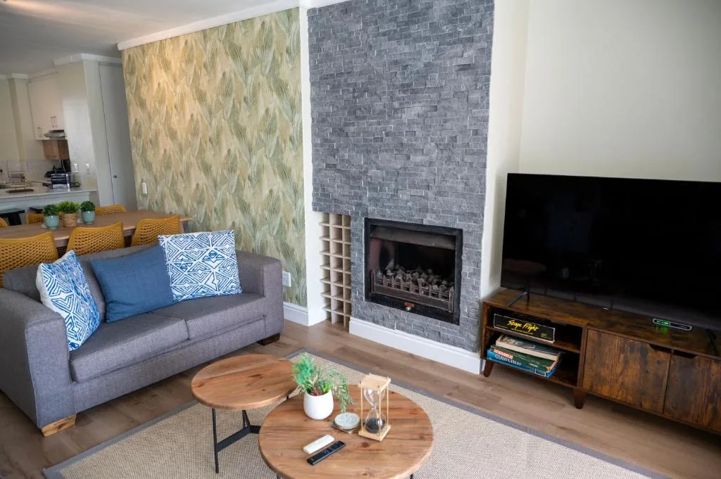 Modern lounge with gray sofa, fireplace, TV, and wooden coffee table
