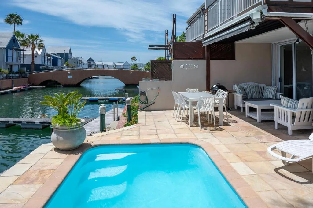 Bright blue swimming pool with canal and bridge views behind