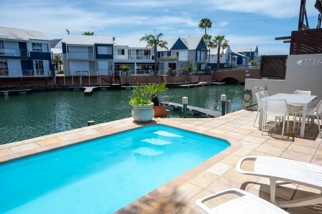 Bright blue swimming pool overlooking lagoon with waterfront houses