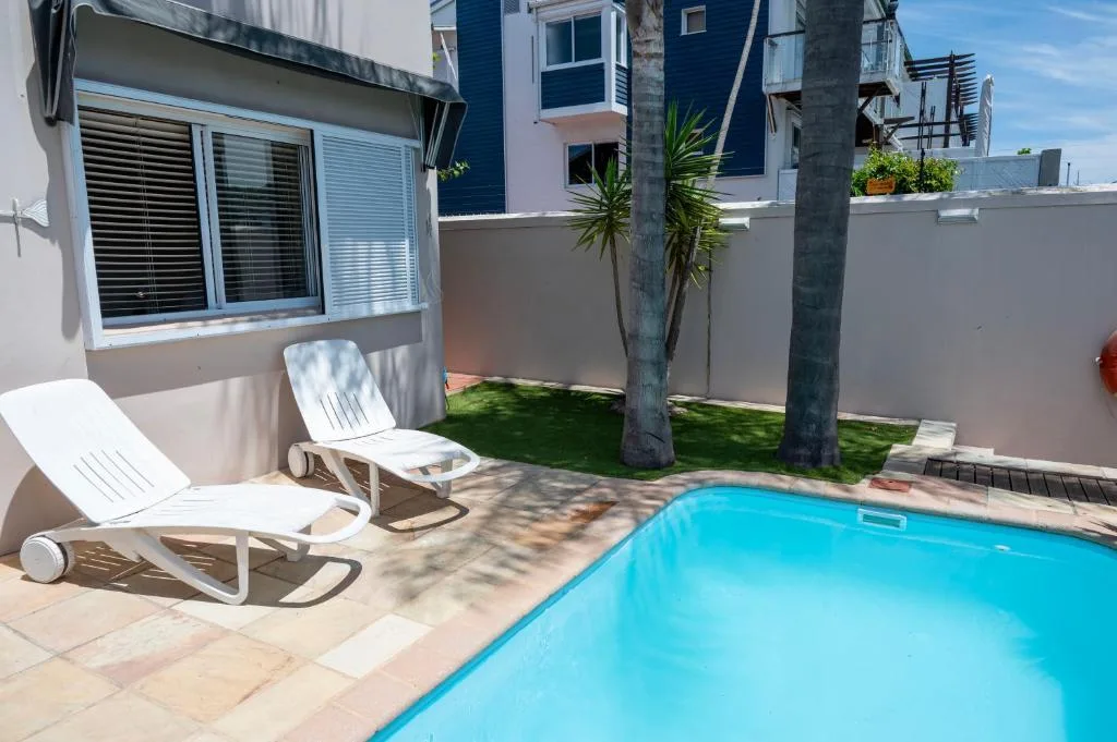 Bright turquoise swimming pool with white loungers and palm trees
