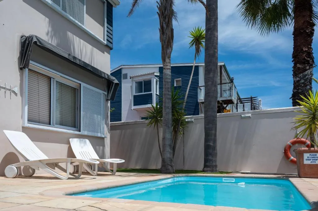 Sparkling blue swimming pool with loungers and palm trees, modern architecture