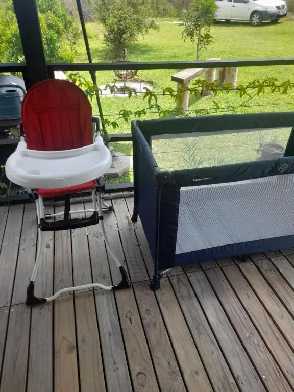 Wooden deck with high chair and portable crib overlooking green lawn