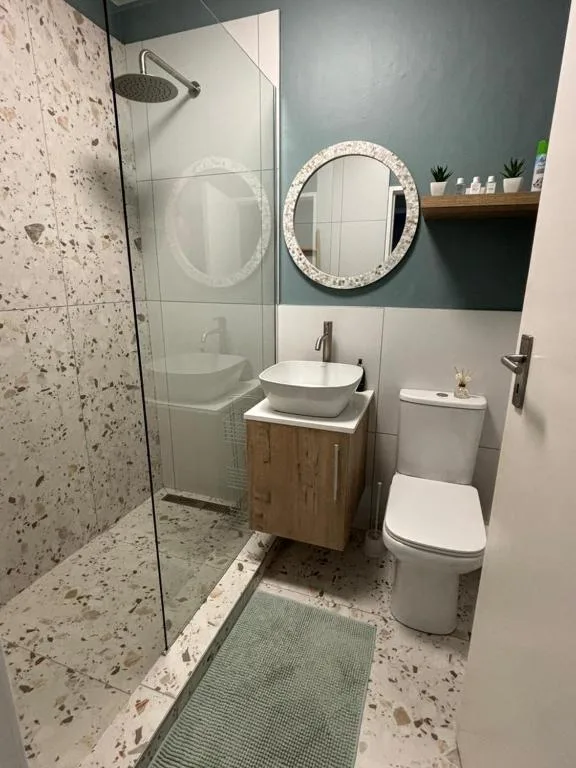 Modern bathroom with walk-in shower, round mirror, white basin and toilet