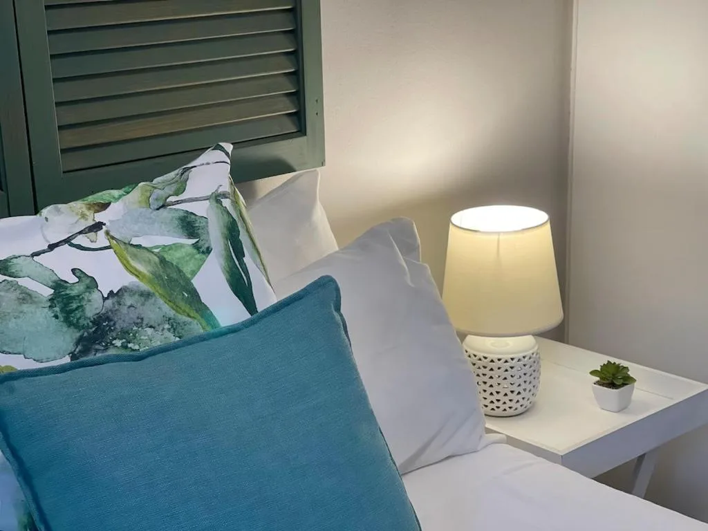 Cozy bedroom corner with blue cushion, white pillows, and bedside lamp