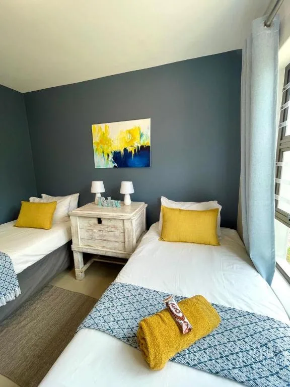 Twin bedroom with yellow cushions, dark accent wall, and shared nightstand