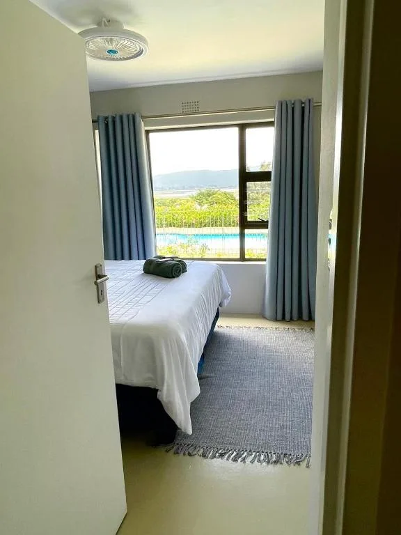 Bright bedroom with single bed, large windows overlooking pool and lagoon views