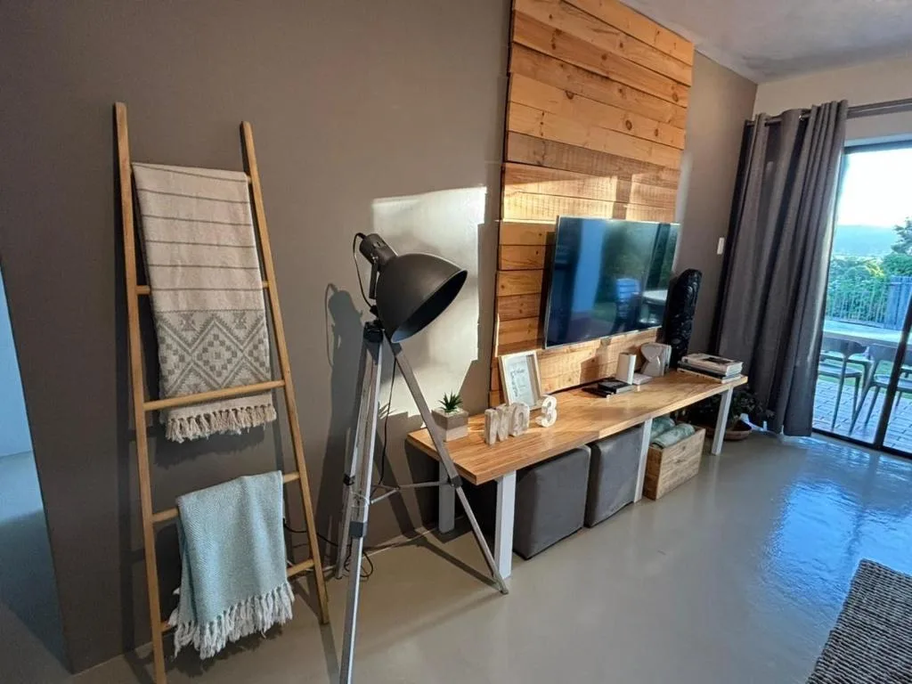 Modern lounge with TV, wooden accent wall, work desk, and ocean view access