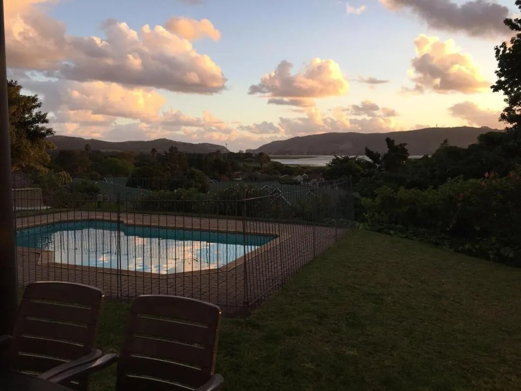 Fenced swimming pool at sunset with lagoon and mountains beyond