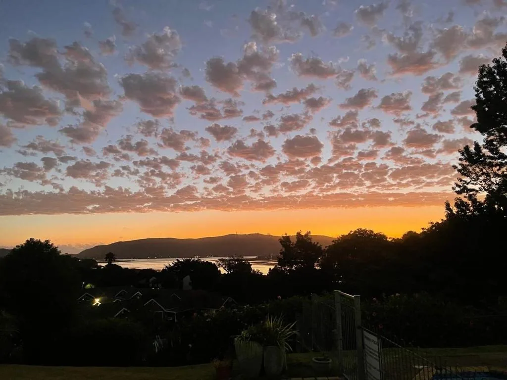 Sunset over Knysna Lagoon with dramatic clouds and mountains silhouetted