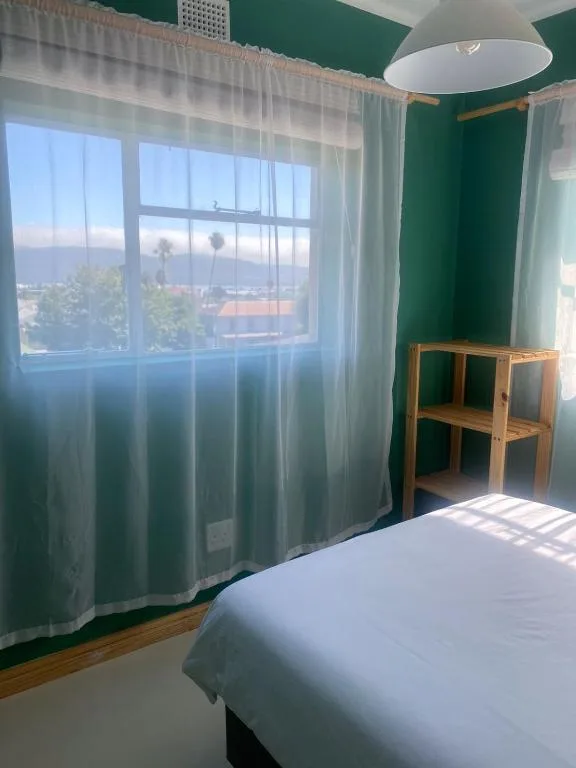 Bright bedroom with white bed, green walls, and expansive window views