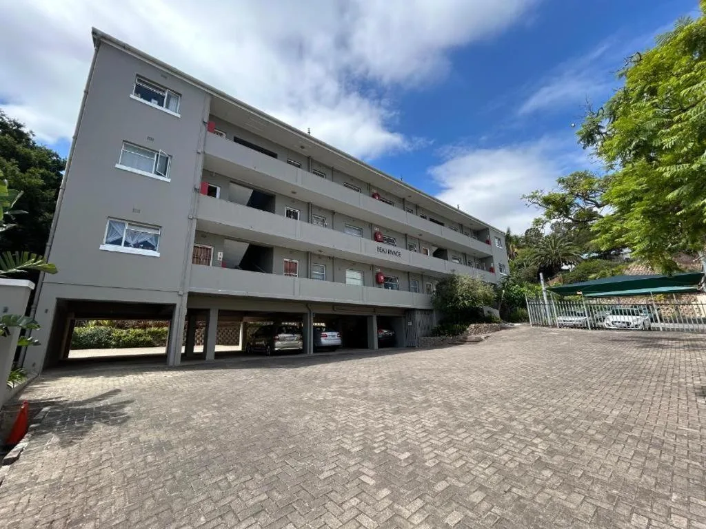 Modern apartment building facade with multiple balconies and ground-floor parking