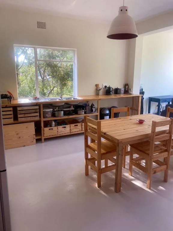 Bright kitchen-dining area with wooden cabinetry, dining table, and garden views