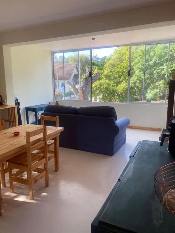 Open-plan lounge with black sofa and wooden dining table, large windows
