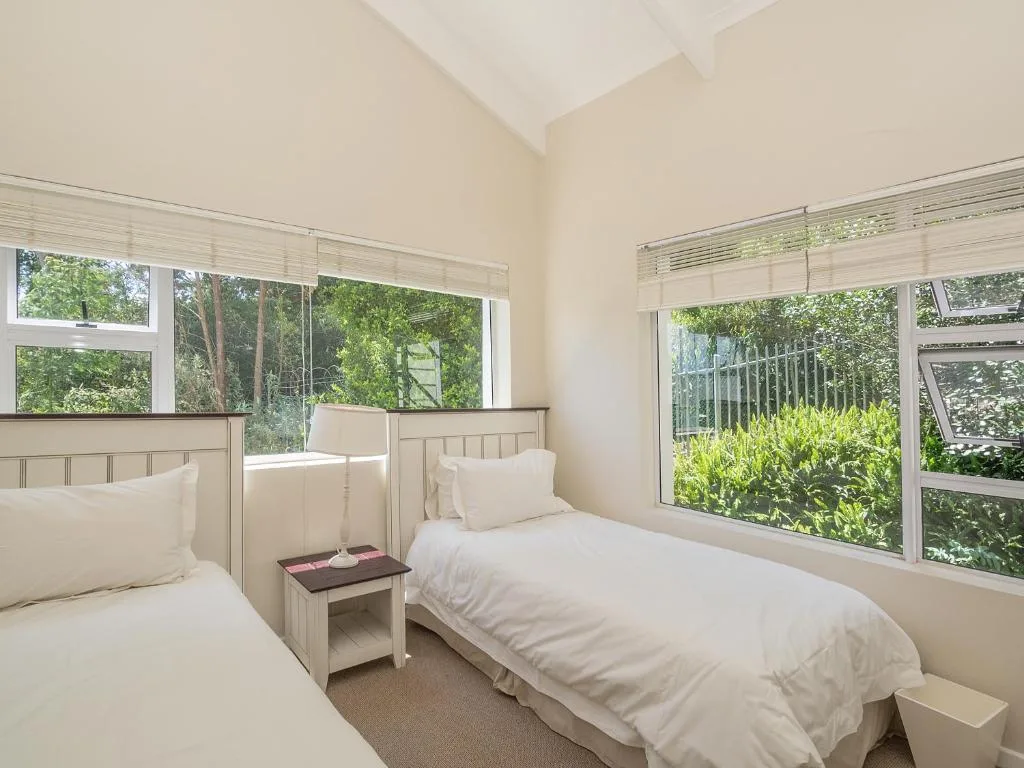 Bright bedroom with twin beds, garden views through large windows