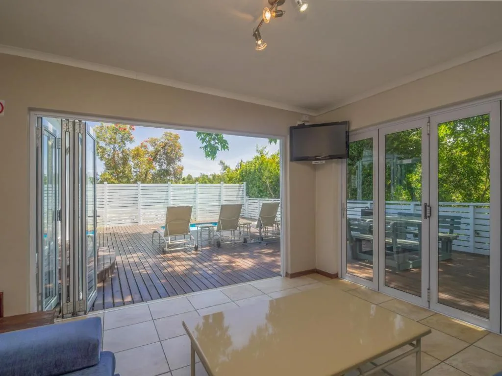Spacious wooden deck with lounge chairs and white railings overlooking trees