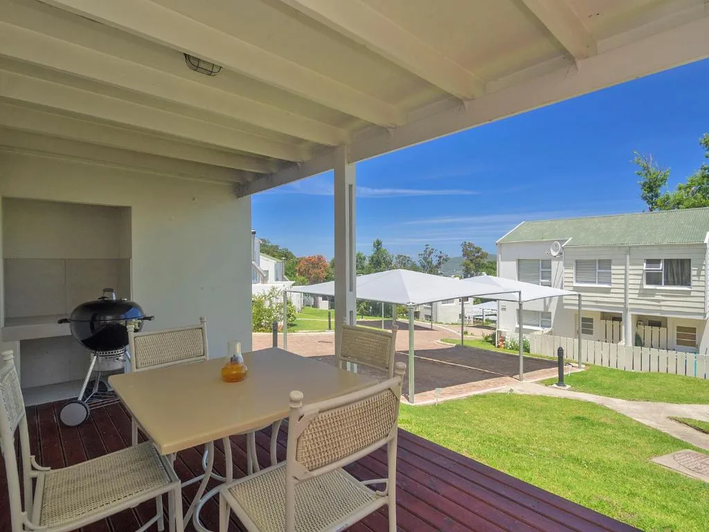 Covered patio with dining table, braai grill, and garden views