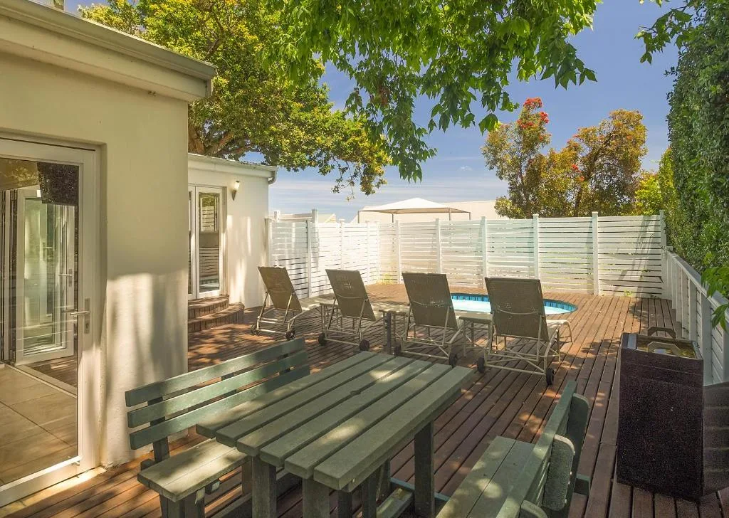 Wooden deck with dining table, lounge chairs, and swimming pool area