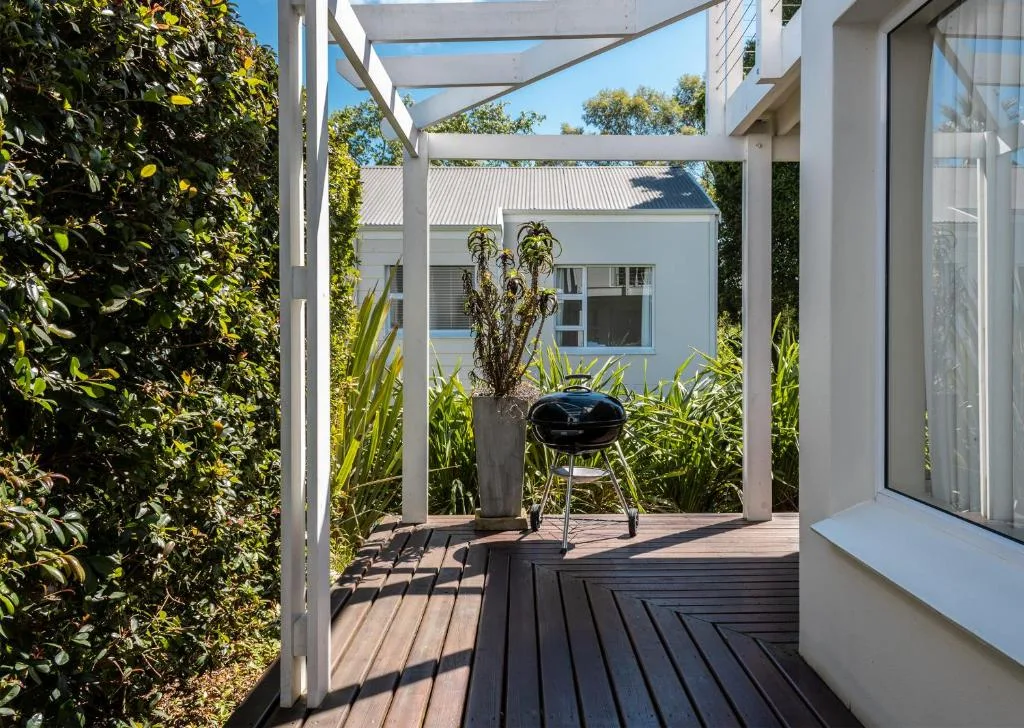 Modern pergola deck with braai grill, potted plants, and garden views