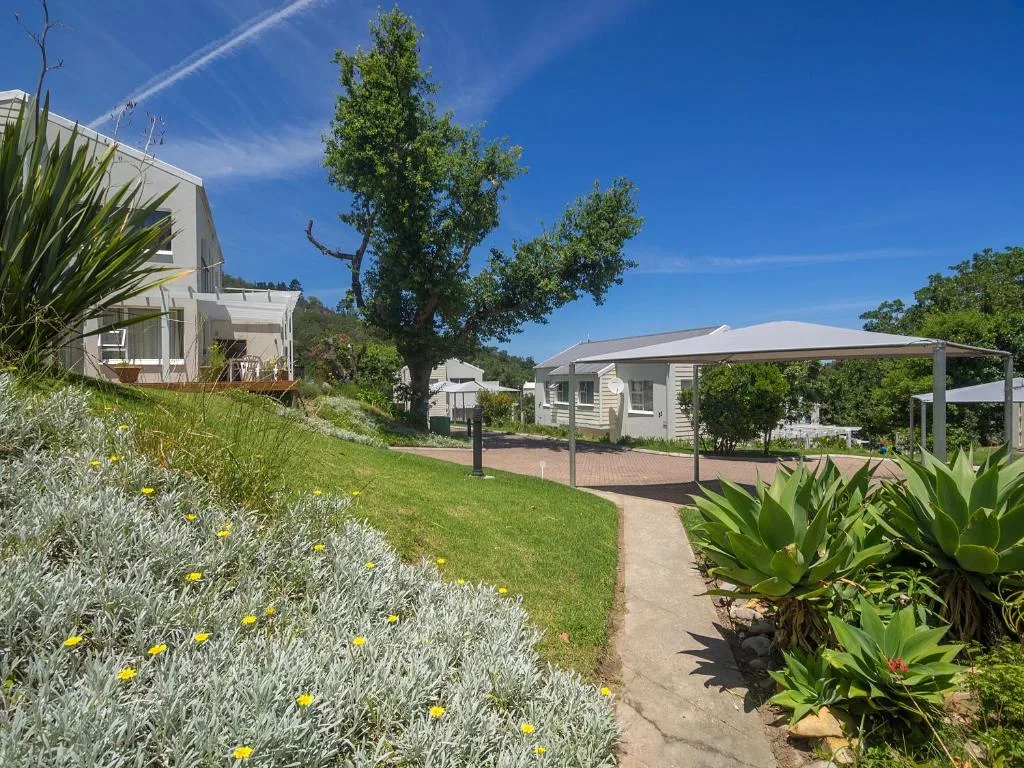 White holiday home with garden pathway and shaded pergola area