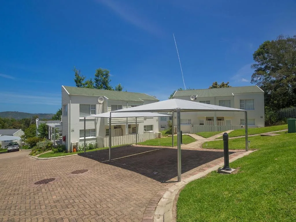 Modern white holiday home with covered parking area and manicured lawns