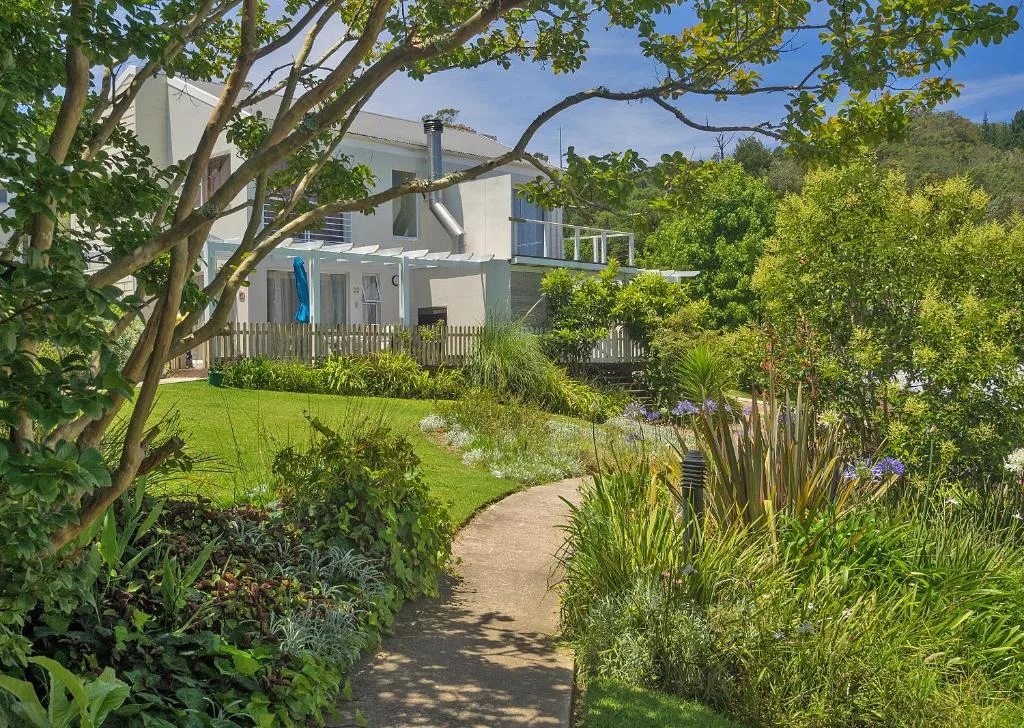 Modern house with white facade surrounded by lush landscaped gardens and trees
