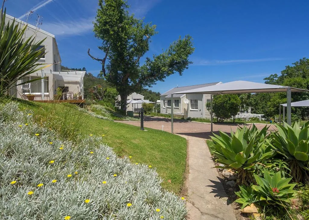 White holiday cottage with manicured gardens and shaded deck area