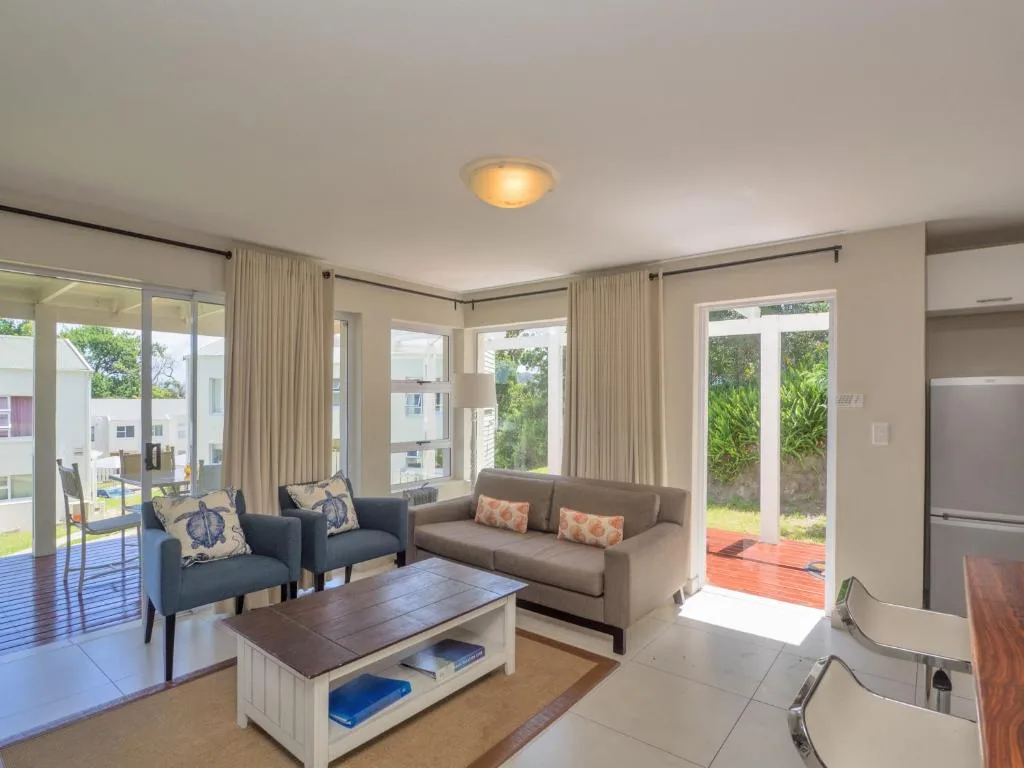 Bright lounge with gray sofa, blue armchairs, wooden coffee table, and garden views