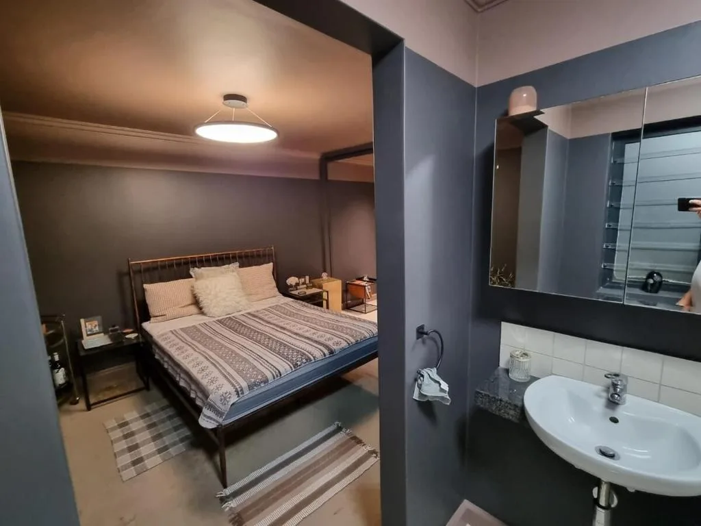 Modern bedroom with queen bed, ensuite bathroom visible through doorway