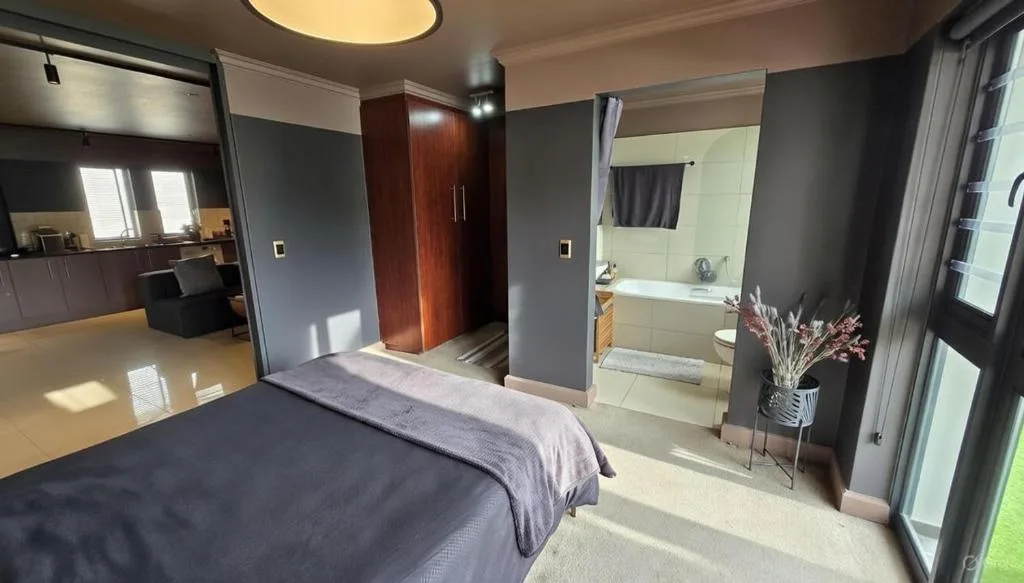 Master bedroom with bed, ensuite bathroom, and kitchenette visible