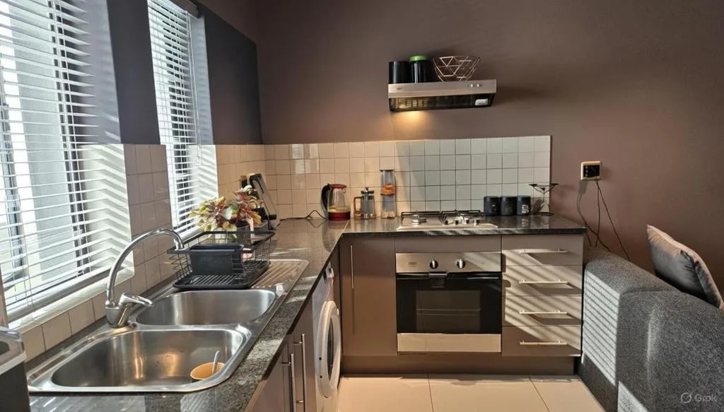Modern kitchen with stainless steel appliances, sink, and white tile backsplash