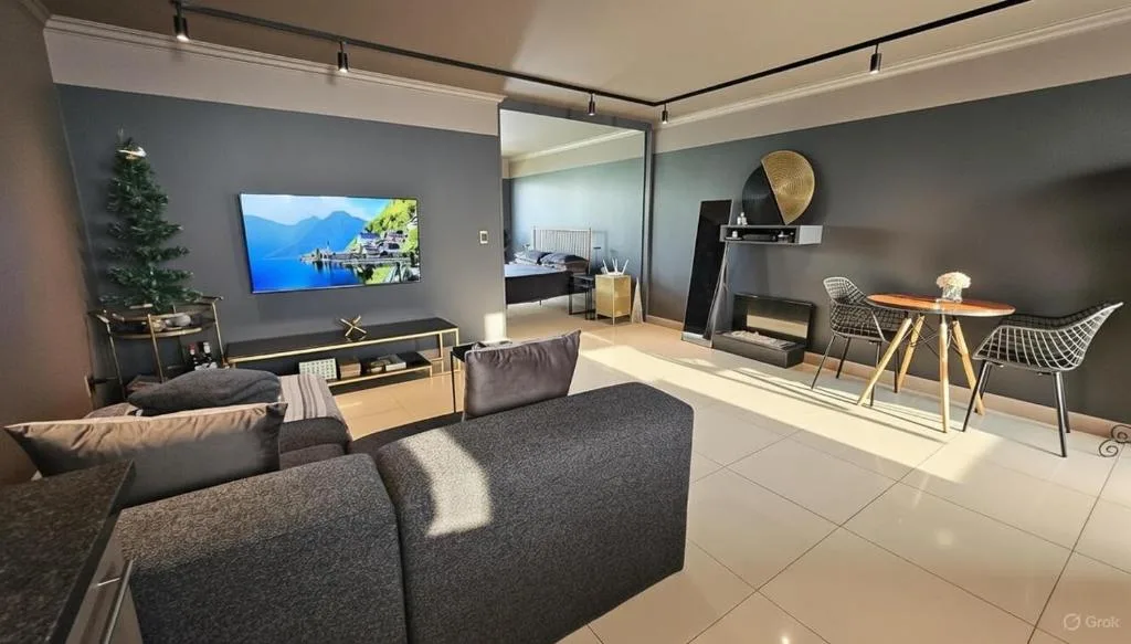 Modern lounge with grey sofas, TV, and dining area visible through open plan design