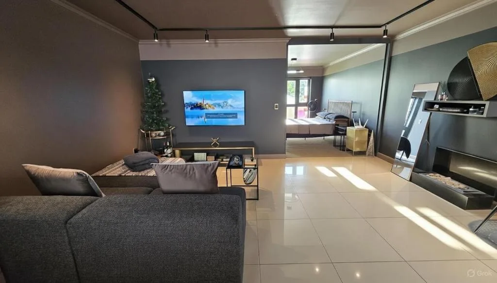 Modern living room with gray sofa, mounted TV, and bright natural light