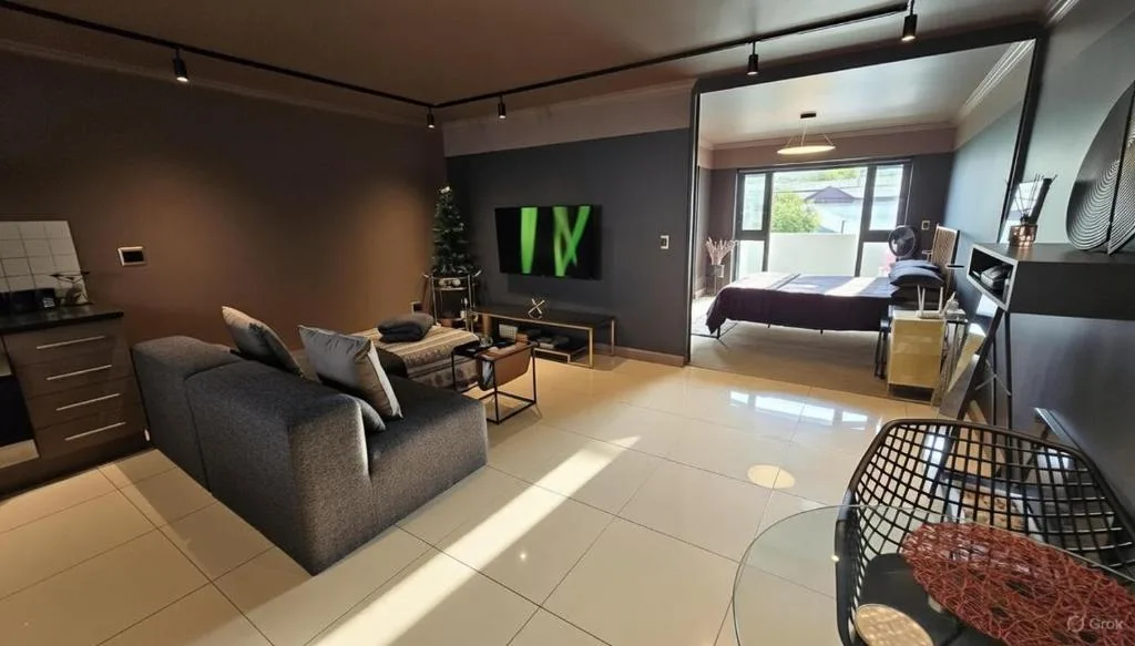 Modern lounge with gray sofa, TV, and bright natural light from windows
