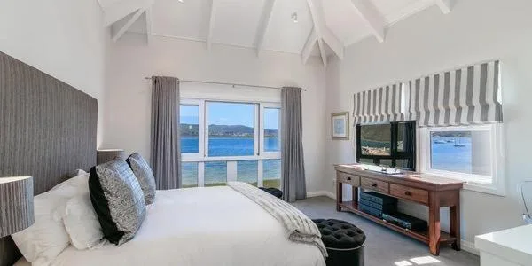 Bright bedroom with ocean views through large windows and coastal scenery