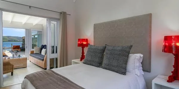 Modern bedroom with waterfront views through glass doors to Knysna lagoon