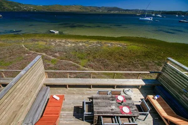 Wooden deck with dining table overlooking tranquil lagoon and sailboats