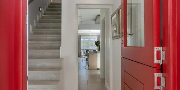 Modern hallway with red cabinetry, stairs, and ocean view through windows