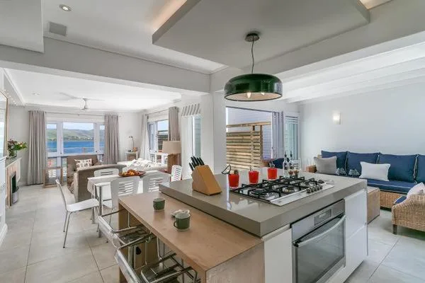 Modern open-plan kitchen with gas stove, wooden island, and ocean views beyond