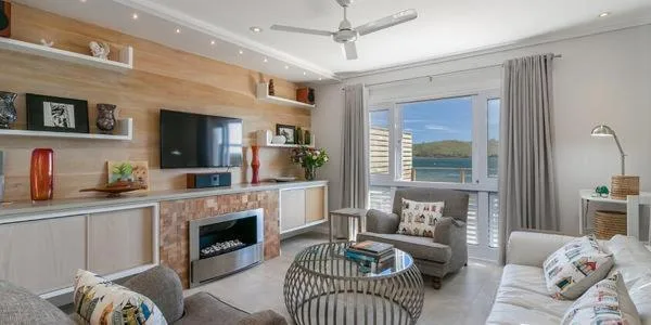 Modern lounge with fireplace, TV, comfortable seating, and water views