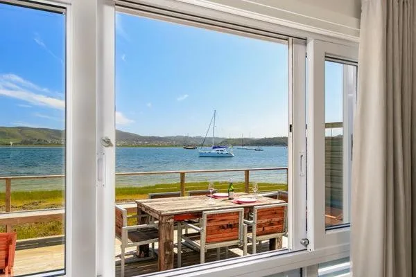 Scenic bay view with sailboat, green hills, and coastal landscape