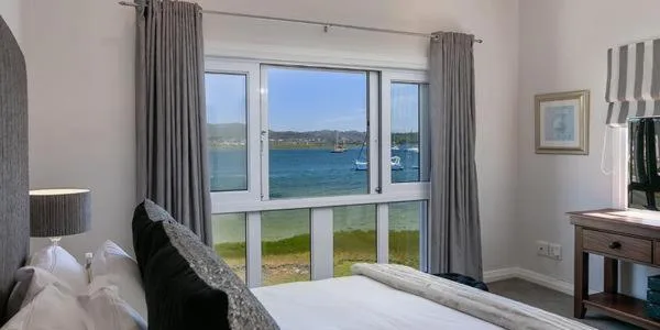 Bedroom with expansive windows overlooking Knysna Lagoon and boats
