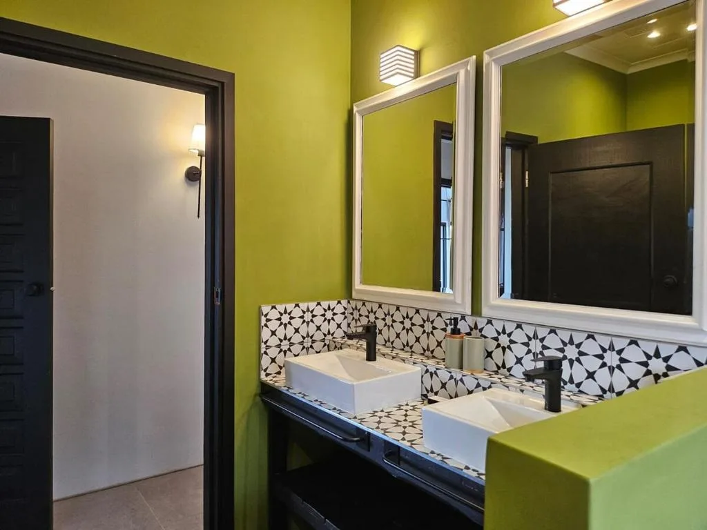 Modern bathroom with dual vanity sinks, geometric tile backsplash, and lime green walls