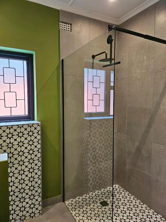 Modern shower enclosure with geometric tile pattern and green accent wall