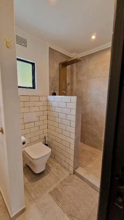 Modern bathroom with wall-mounted toilet, subway tile, and walk-in shower