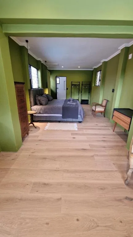Spacious bedroom with wooden floors and lime green walls