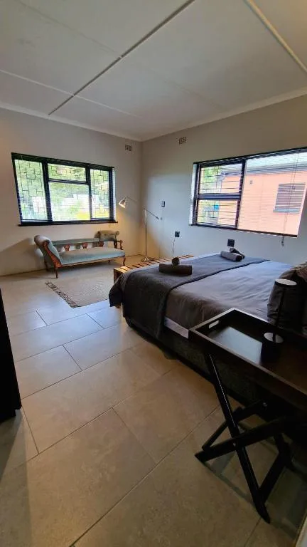 Spacious bedroom with double bed, seating area, and multiple windows with natural light