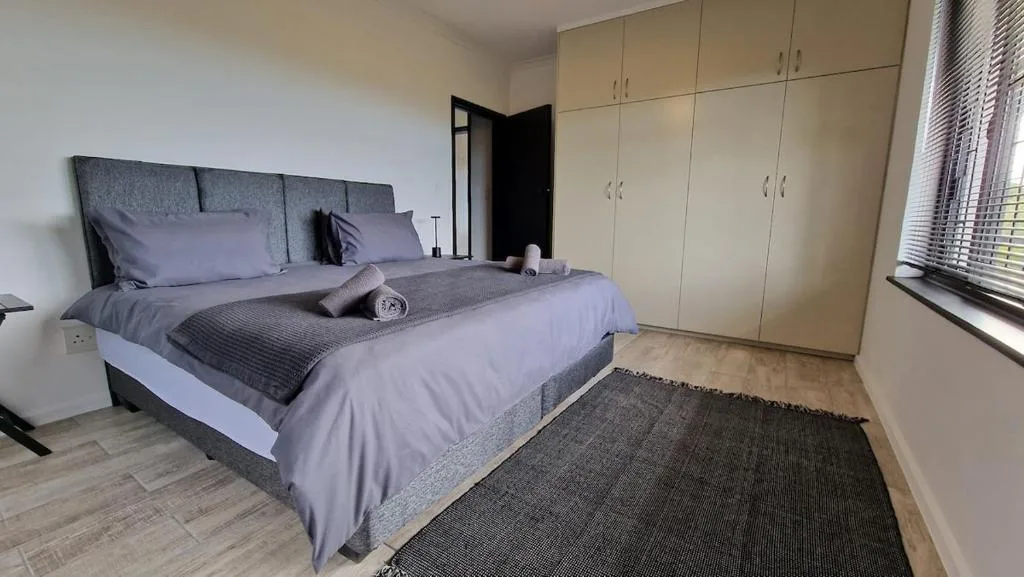 Modern bedroom with gray upholstered bed and built-in cream storage cabinetry